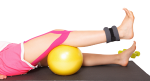 Piernas en camilla haciendo rehabilitación con pelota y tobillera