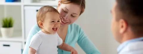 Mamá con bebé sonriendo y doctor