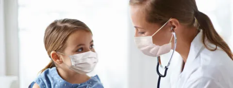 Mujer pediatra auscultando una niña