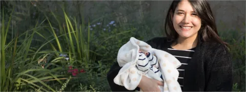 Mujer joven sonriente cargando a su bebé recién nacido