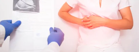 Paciente con sus manos en el abdomen