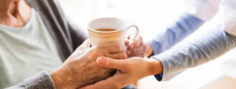Manos de mujer joven sosteniendo manos de mujer adulta. Esclerosis Lateral Amiotrófica (ELA)