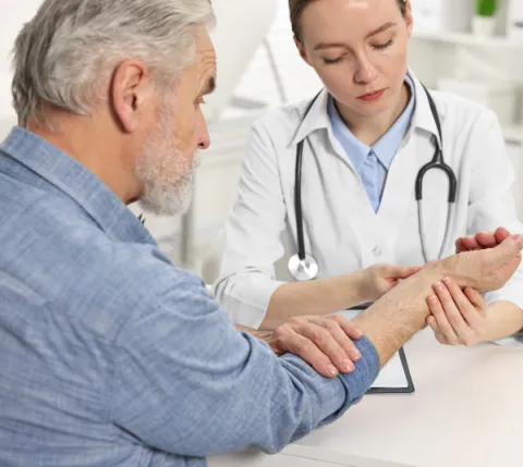 Médica examinando la mano de un hombre mayor