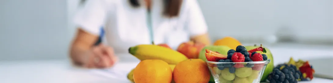 Médica anotando en mesa con frutas