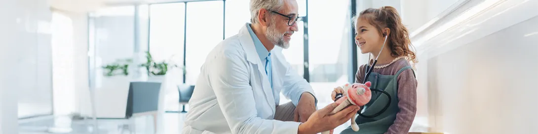 Médico dando un peluche a una niña