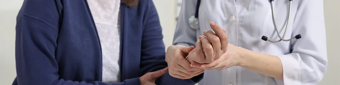 Médica examinando la mano de una mujer