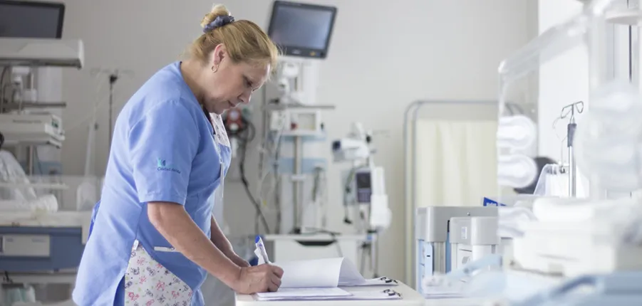 Mujer con uniforme sanitario en sala con equipamiento médico