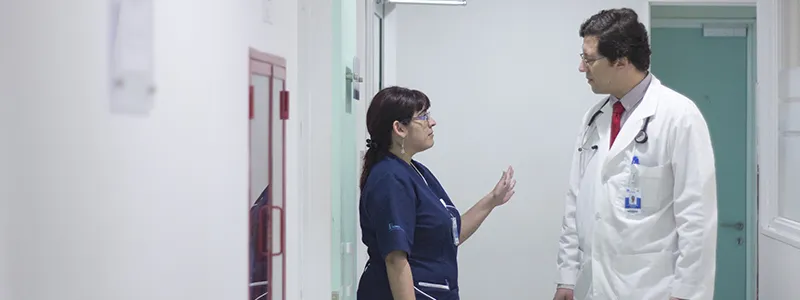 Doctora y doctor conversando en clínica