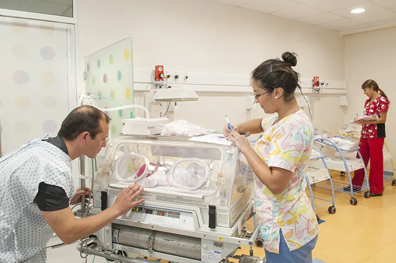 Profesionales de salud atendiendo a bebé en incubadora